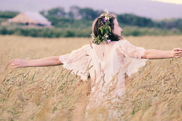 A care-free, happy woman standing in the middle of a field with arms spread