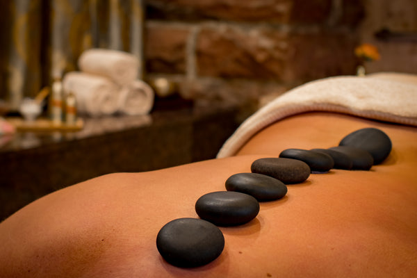 Massage stones placed on the back of a woman in a massage room